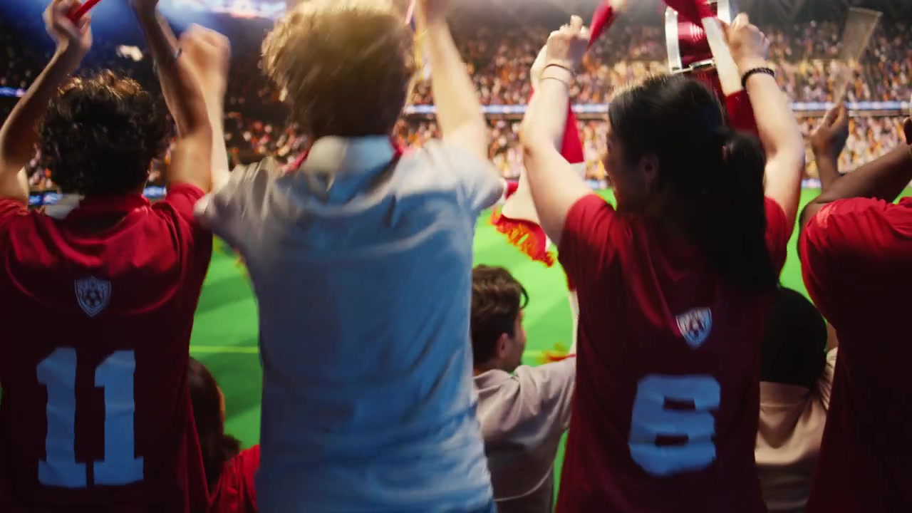 Primer plano de aficionados con camisetas rojas animando en las gradas del estadio.