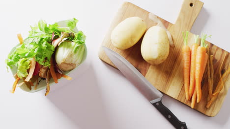 vídeo aéreo de cuchillo y verduras en la tabla de cortar, con residuos vegetales en bolsas para compostaje