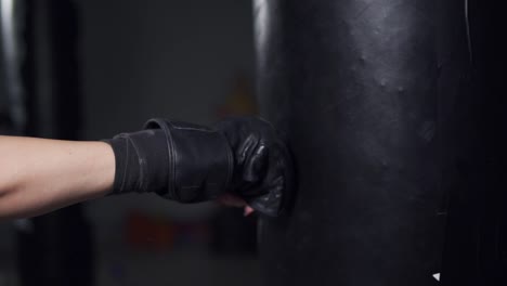 close up view of a woman's hand in boxing gloves punching a bag in a boxing club. slow motion shot