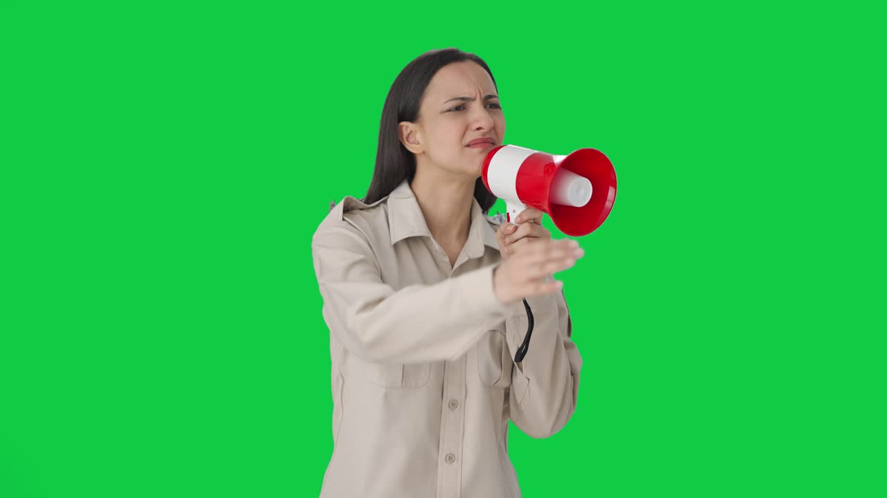 Poliziotta indiana che urla alla gente usando un megafono. Schermo verde