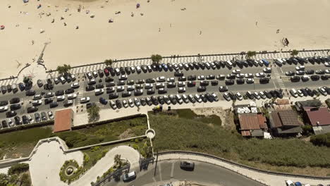 top view of coastal avenue with huge car parking area situated next to obidos mouth lagoon and foz do arelho beach in portugal - aerial drone descending