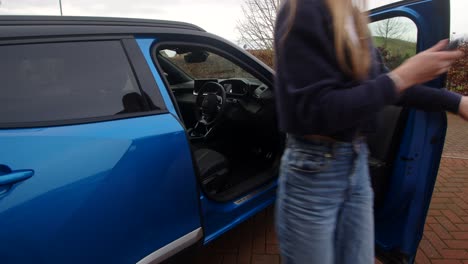 female-model-getting-out-of-a-blue-electric-car-and-locking-the-car-with-the-car-fob