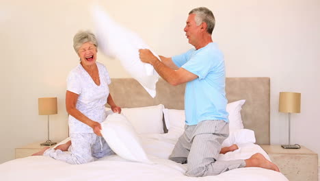 happy senior couple having a pillow fight
