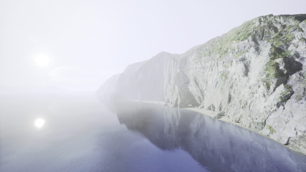 Foggy coastal view revealing rocky cliffs and calm water at dawn