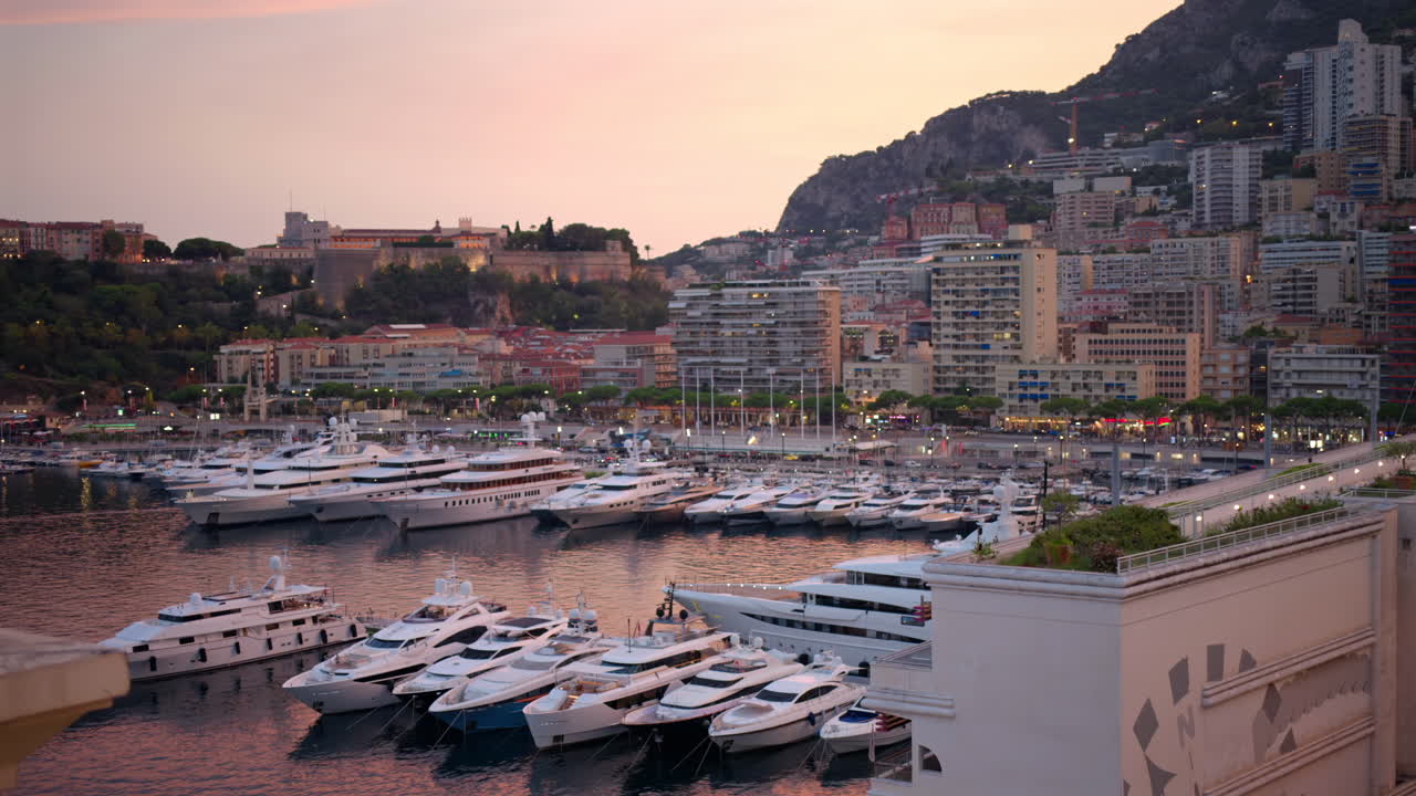 Paesaggio urbano di Monaco al tramonto. Porto marittimo con yacht ormeggiati, edifici residenziali e strade illuminate