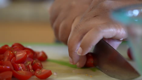 focus pull to reveal the hands of a black woman cutting cherry tomatoes for a chopped salad - antipasto salad series