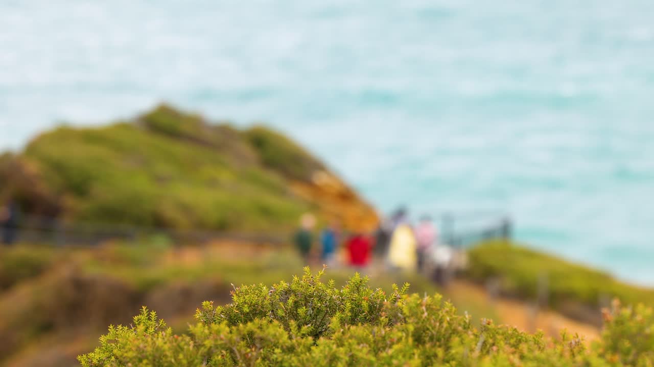 People walking on a coastal path with ocean views, vibrant colors, and natural lighting. Captured at Aireys Inlet, Australia