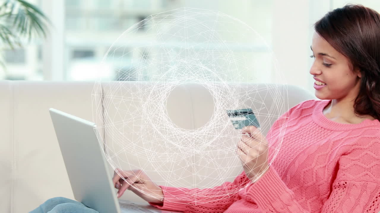 animación de globo de red de conexiones sobre mujer biracial con tarjeta de crédito usando portátil.
