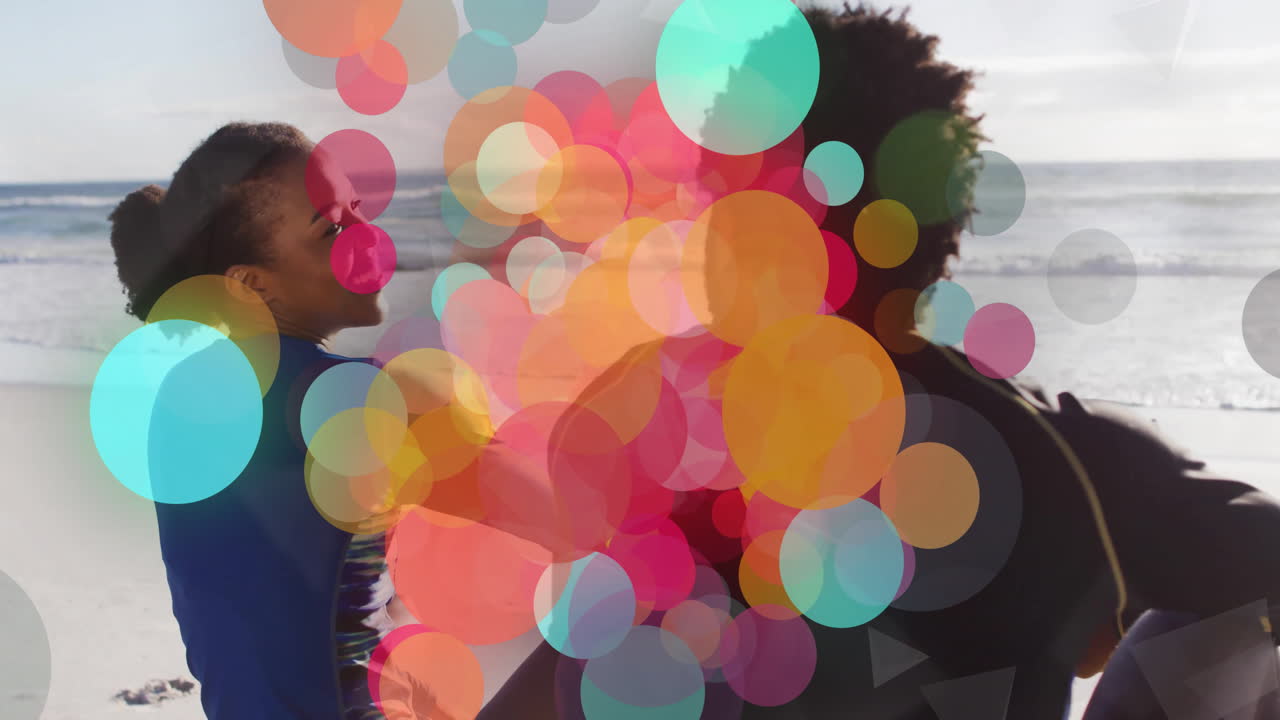 Colorful circles animation over two people enjoying time at beach