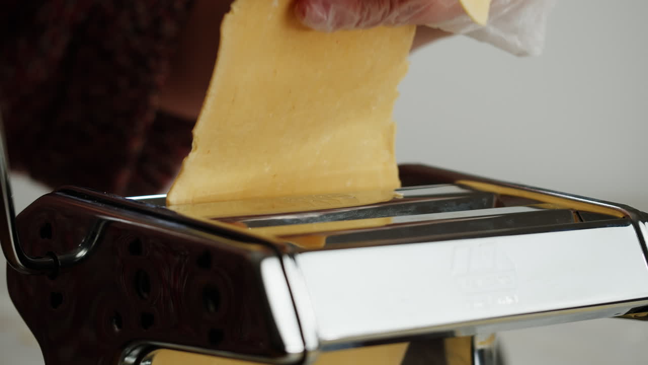 Person Rolling Homemade Pasta Dough Through a Machine