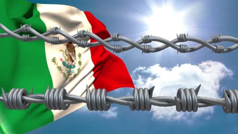 alambre de púas contra la bandera mexicana ondeando