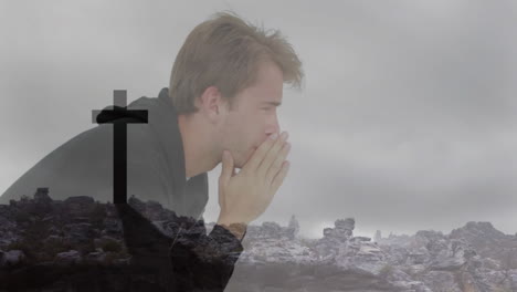 man praying with hands covering face over cross and rocky landscape animation
