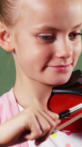 schoolgirl playing violin in classroom at school