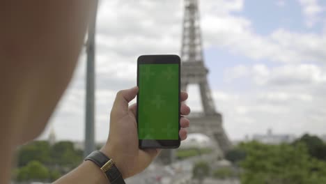 man using smartphone with green screen at eiffel tower, touchscreen with tracking markers. browsing internet, watching media content, videos, blogs, social networks. 4k uhd. paris.