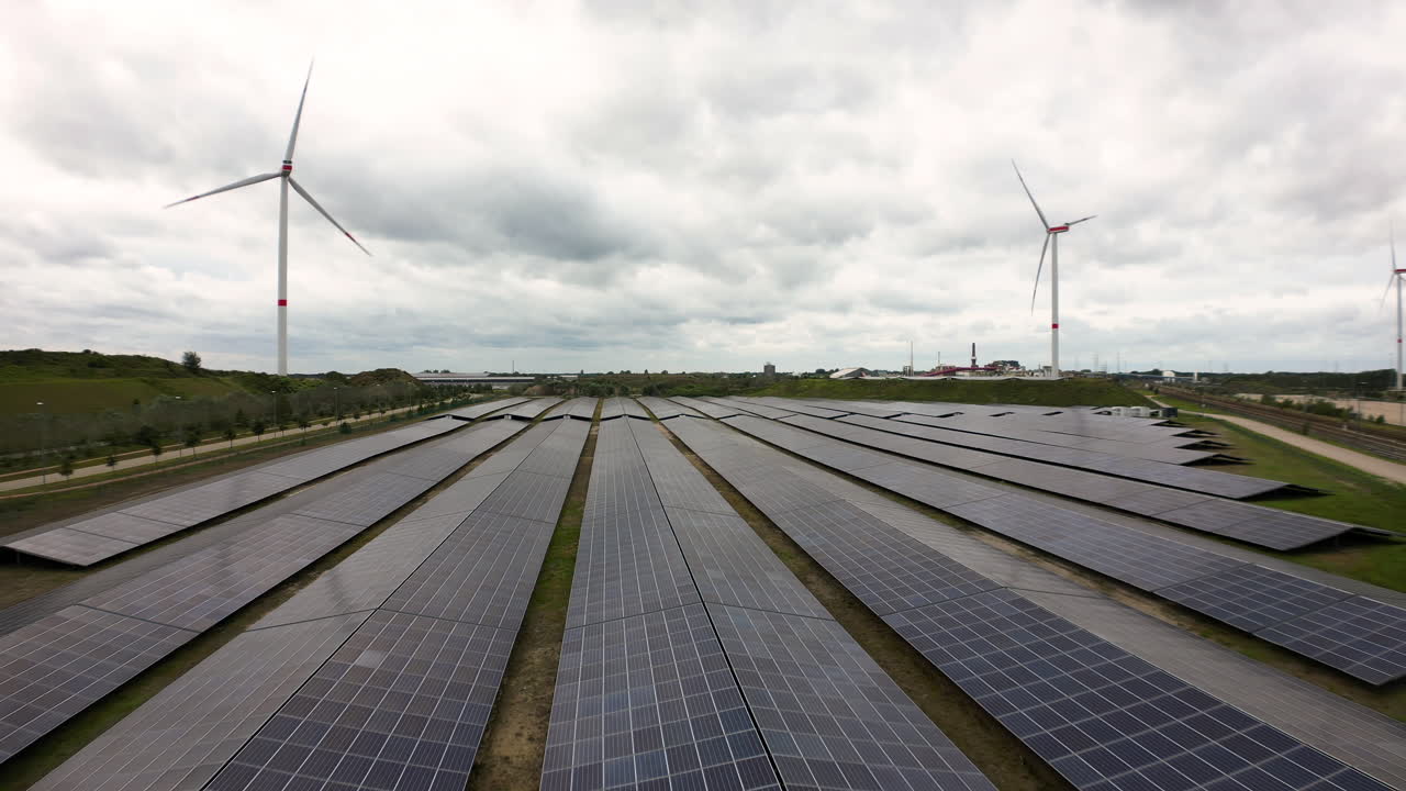 Wind turbines and solar panels on moody day, aerial view