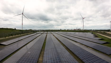 Wind-turbines-and-solar-panels-on-moody-day,-aerial-view