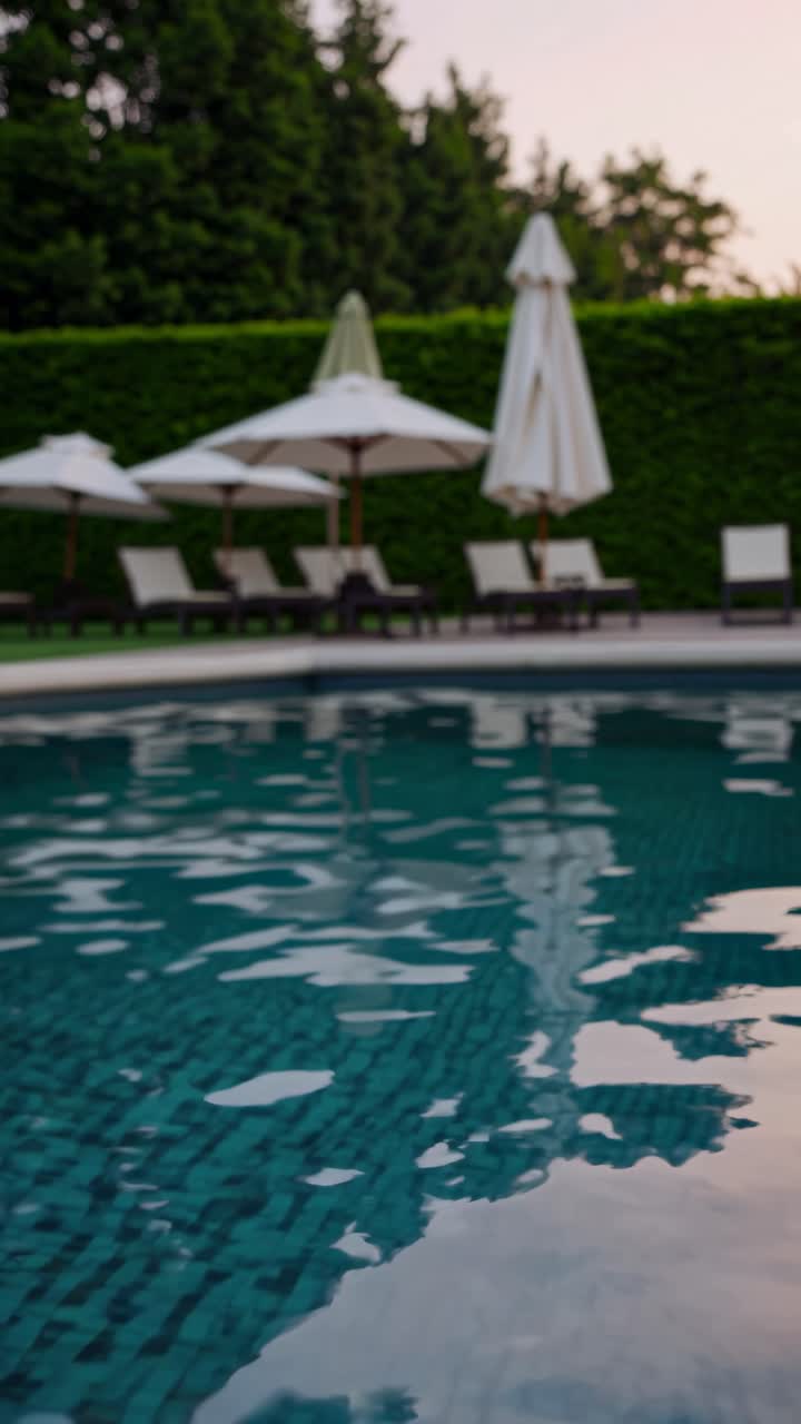 A serene poolside scene captured at a low angle, showcasing reflections on the water