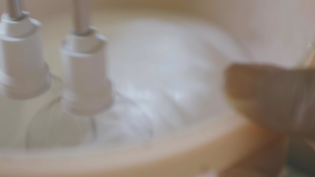 반지를 끼고 있는 여성이 분홍색 그릇에 달걀 흰자위를 휘젓는 슬로우 모션