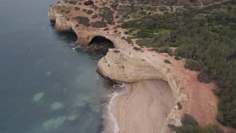 vista aérea descendiendo sobre las cuevas de benagil, lagoa, algarve portugal con la costa transparente del océano atlántico