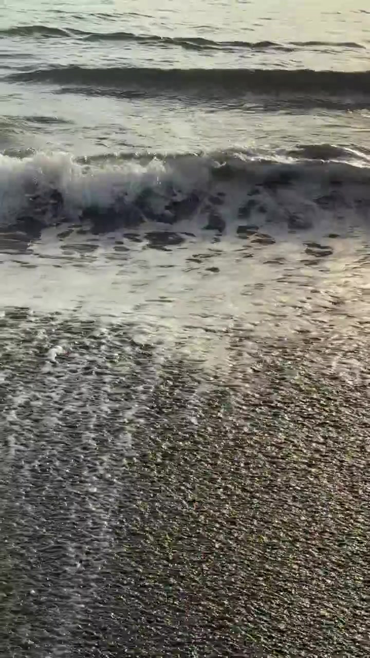 Dolci onde dell'oceano che si infrangono su una spiaggia sabbiosa con riflessi del sole