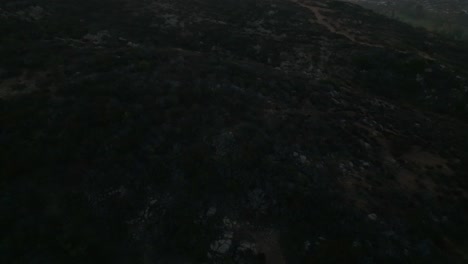 Aerial-view-of-hiking-trail-on-Cowles-Mountain-during-the-sunrise-tilting-up-revealing-neighboring-city-of-San-Carlos-and-switchbacks-in-San-Diego-California,-USA