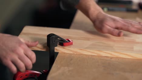 close-up of male hands clamping the board with carpentry clips