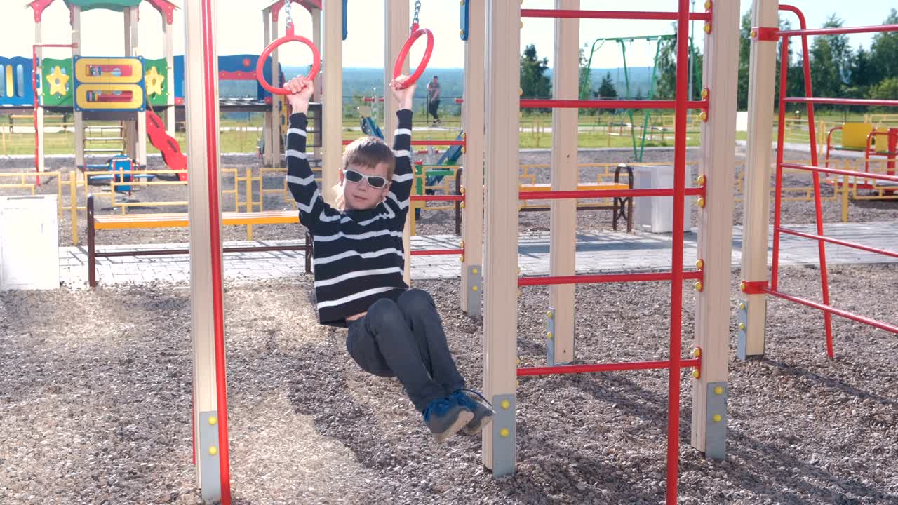 Seven-year-old boy spinning on the gymnastic rings on the Playground.