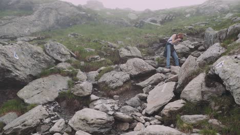 a young woman hiker climbs mountains with photo camera. transfagarasan, carpathian mountains in romania