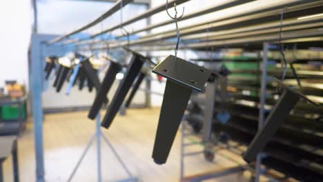 freshly powder coated metal parts hang to dry in factory