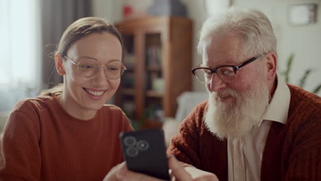 elderly man learning to use mobile app on smartphone with help from daughter