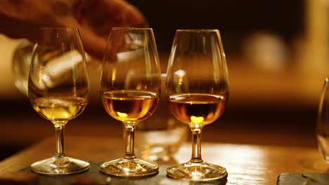 pouring whisky into glasses for tasting