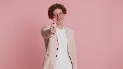 young man with curly hair and glasses giving thumbs up