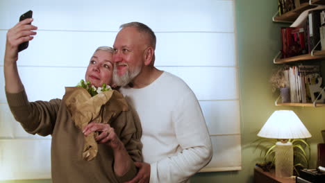 una pareja tomando una selfie con un ramo de flores.