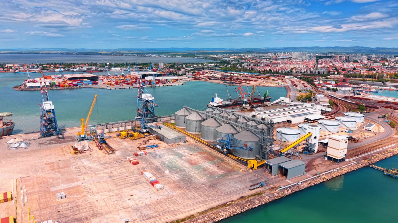 Veduta aerea di un terminal portuale merci con silos per cereali. Veduta dall'alto di un porto marittimo industriale con silos metallici per lo stoccaggio di cereali, gru e container.
