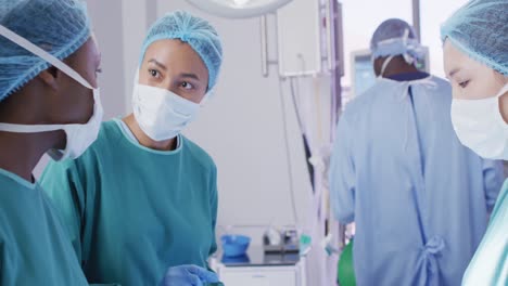 Video-of-three-diverse-female-surgeons-talking-during-operation-in-theatre,-copy-space