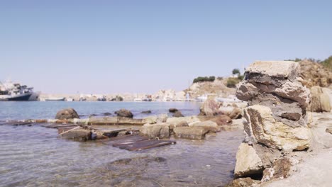 serene coastal scene with clear blue water, old ruins and broken wooden planks on shore.