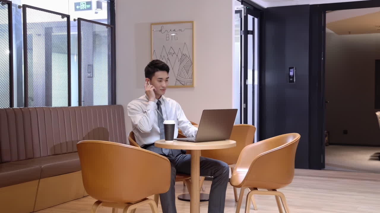 Pengusaha percaya diri dengan earphone di lobi kantor, minum kopi dan bekerja di laptop. Bersiap untuk rapat virtual atau panggilan daring. Bersiap bergabung dalam konferensi atau memulai webinar