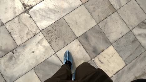 a person feet covered walking on tiled floors of taj mahal mausoleum in agra, india. pov shot
