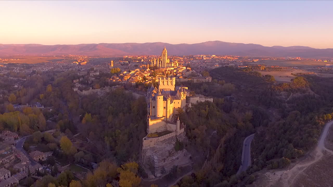 alejando la vista aérea del alcázar de segovia y la ciudad durante el otoño con hermosos colores de árboles y puesta de sol