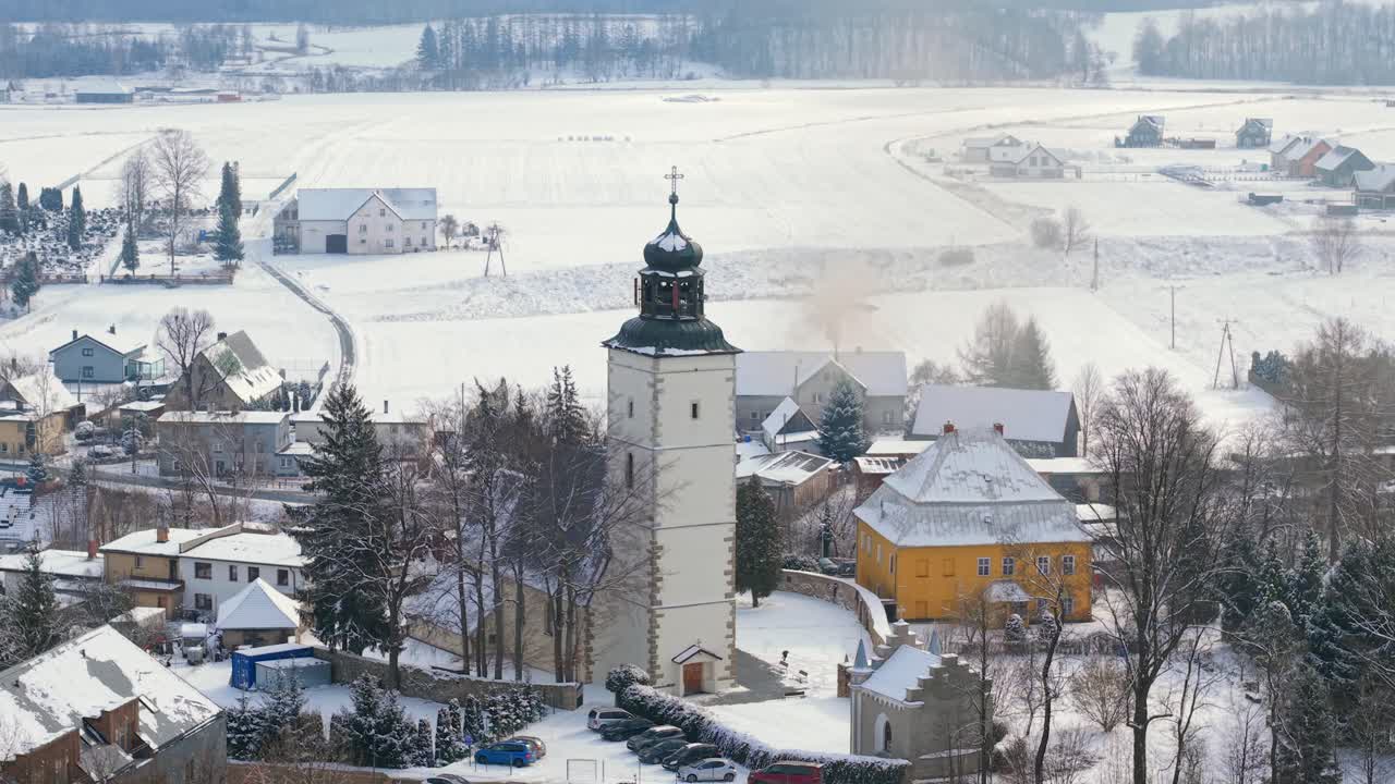 Drone establishing medium orbit of historic old church in Lomnica, Poland, surrounded by snow