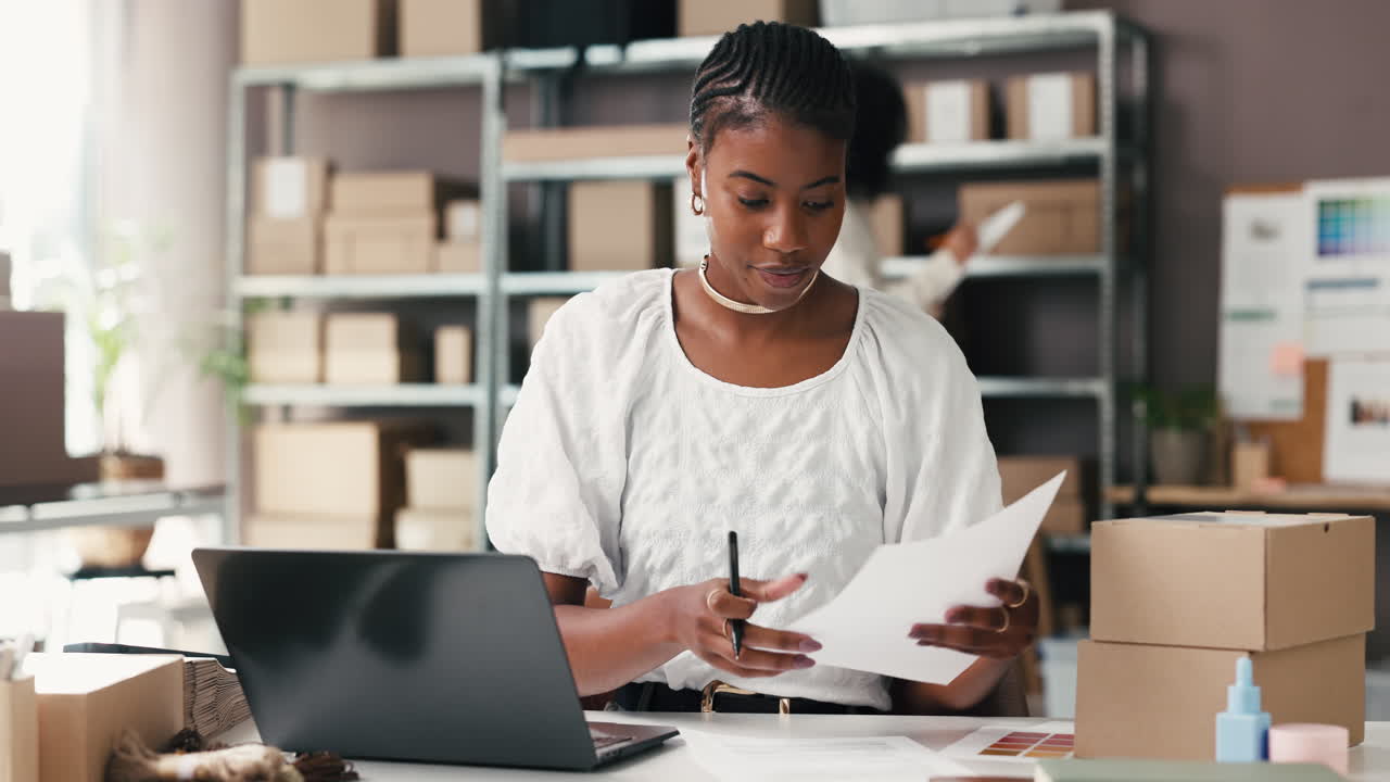 Young Black Woman Managing Orders and Inventory in Small Business Office