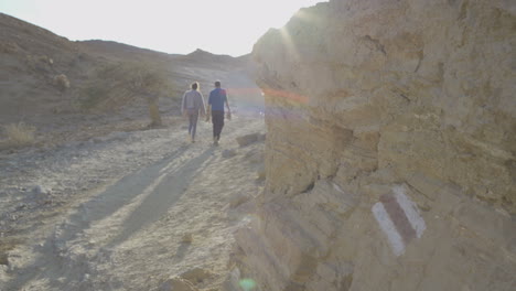 dos personas pasando junto a una marca de sendero en el desierto