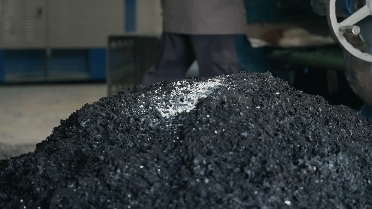 Large pile of processed crumb rubber inside an industrial recycling facility