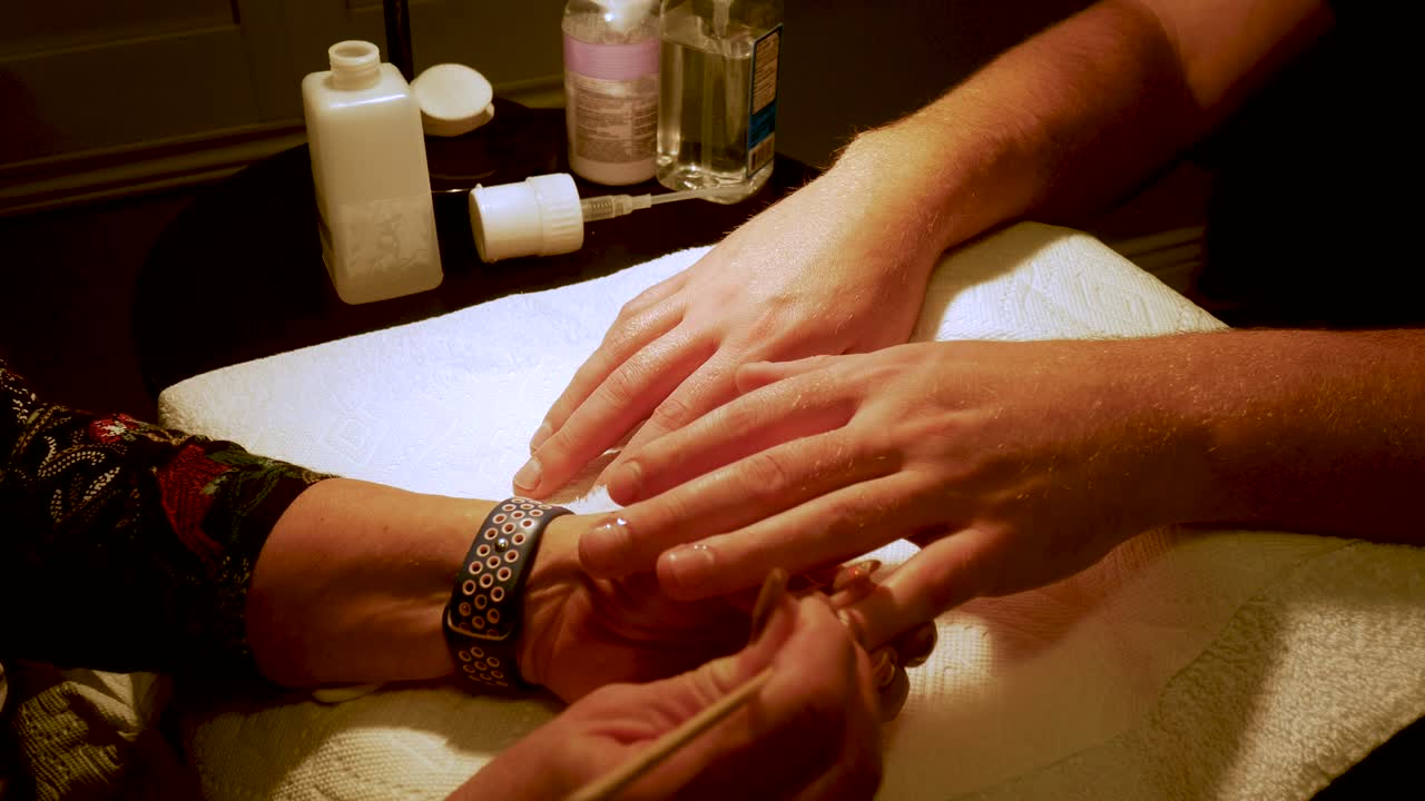 Primo piano delle grandi mani di un uomo che si fa fare una manicure.