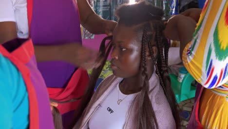 Young-woman-sitting-pensive-as-three-beauticians-style-her-extensions