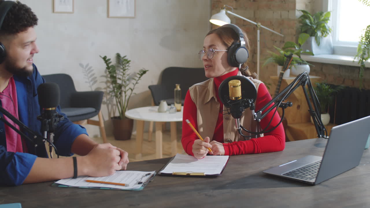 Two Podcast Presenters Speaking into Mics in Recording Studio