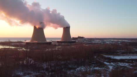 Dolly-Right-Aerial-Drone-Shot-of-Nuclear-Power-Plant-Cooling-Towers-at-Sunrise-Sunset-with-Steam-and-Smoke-Winter