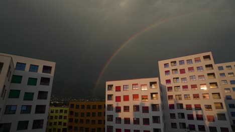 El-Cielo-Oscuro-Se-Transforma-En-Un-Arco-Iris-De-Colores,-Iluminando-Edificios-Residenciales-En-Una-Cautivadora-Escena-Nocturna-Urbana.