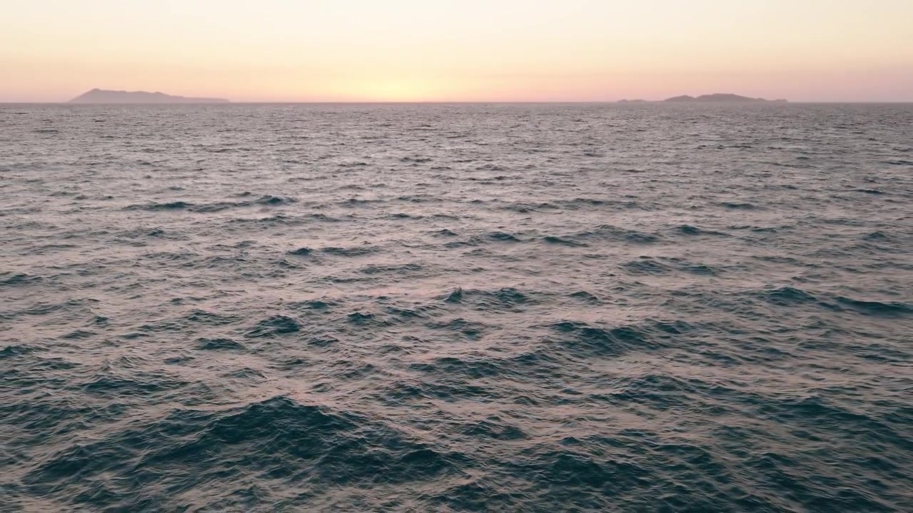 Vista aerea ravvicinata delle onde blu dell'oceano che si infrangono nel Mar Ionio al crepuscolo