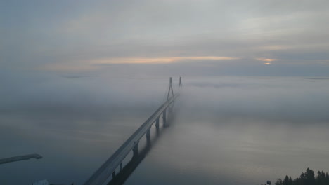 motorbike on bridge over endless ocean driving into haze on cold blue morning